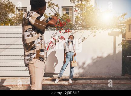 Photographer with model for summer fashion photography taking photo, posing and smiling for portrait shot with lens flare. African creative freelancer Stock Photo