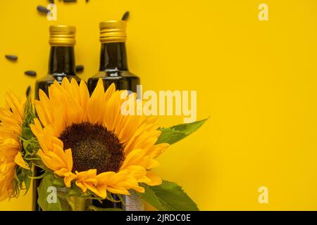 Sunflower oil. Oil bottles, scattered black sunflower seeds and sunflowers on a yellow background.Sunflower oil mockup. Organic natural farm sunflower Stock Photo