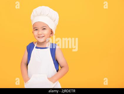 Happy boy in chef uniform on yellow background Stock Photo