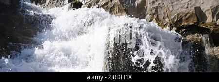 Rapid waterfall with foaming water in rocks background Stock Photo