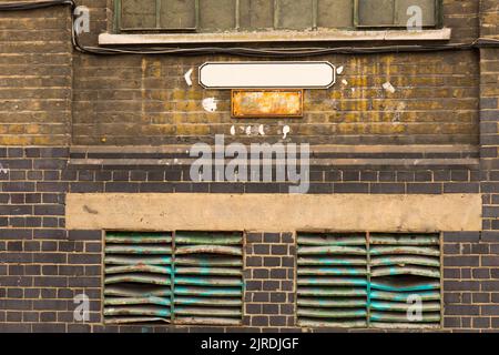 Close up of colorful different colored unkempt weathered old brick factory wall facade with two central mounted signs copy space to write on old parti Stock Photo