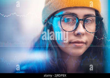 Investments and stock trading. Closeup portrait of a young businesswoman wearing eyeglasses looking at charts and diagrams, double exposure. The conce Stock Photo