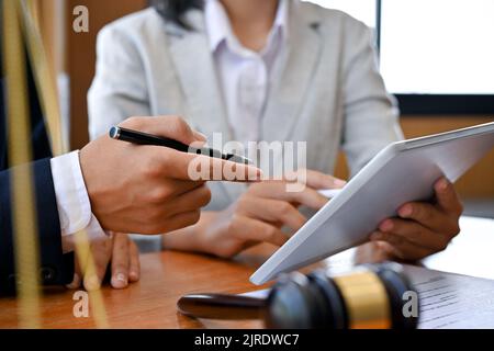 Professional and expert male lawyer or business legal consultant giving an advice, counseling to a female client, using digital tablet, looking at the Stock Photo