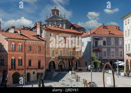 Mondovì, Cuneo, Piedmont, Italy - August 08, 2022:  Ancient medieval buildings with mullioned windows with frescoed brick facades and cathedral in Pia Stock Photo