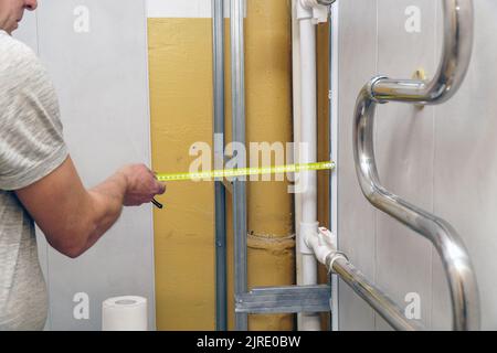 A man with a tape measure measures the wall for reconstruction. Man or builder with tape measure Stock Photo