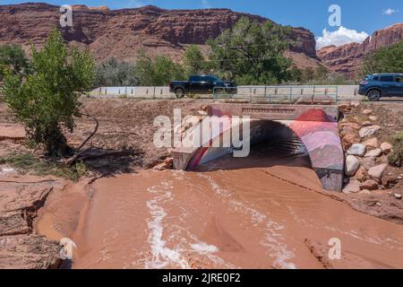 Low drone view of receding flood waters still flowing over the flooded Mill Creek Parkway the day after a flash flood in Moab, Utah. Stock Photo