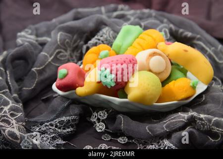 Close-up of a plate with fruit-shaped marzipan figures wrapped in a handkerchief. Typical gift for lovers to celebrate San Dionisio in Valencia (Spain Stock Photo