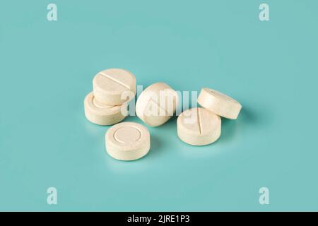 Pile of white tablets scattered on a cyan background Stock Photo