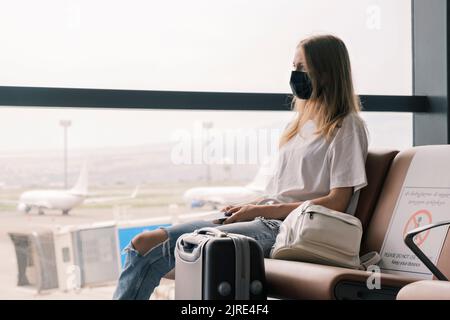 Biometric Ukrainian passport is in hands of woman waiting for flight at the airport. Citizen of Ukraine is forced to leave her home because of war Stock Photo