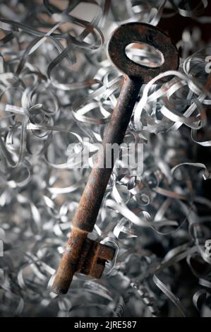 vintage rusting old door key laying on bed of engineering lathe swarf Stock Photo
