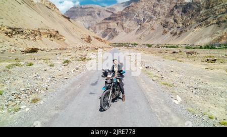 happy guy on motorcycle on desolate dry mountain road in desert of Spiti Valley Himachal Pradesh Stock Photo