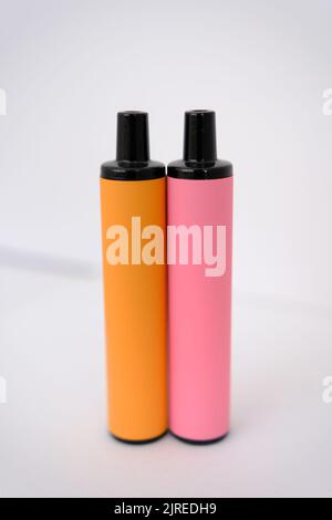 pink and orange disposable electronic cigarettes on white background. Copy space. Stock Photo