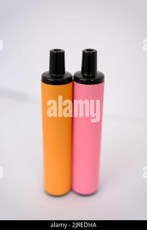pink and orange disposable electronic cigarettes on white background. Copy space. Stock Photo