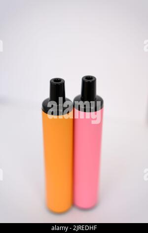 pink and orange disposable electronic cigarettes on white background. Copy space. Stock Photo