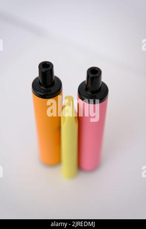 pink, orange and little yellow disposable electronic cigarettes on white background. Copy space. Stock Photo