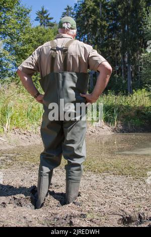 Where the water is normally a meter and fifty deep, the fisherman stands now only ankle-deep in the mud. Stock Photo