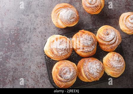 Modern fashionable pastries scones cruffins puffmaffin a mixture of a croissant and maffin closeup in the muffin pan on the table. Horizontal top view Stock Photo