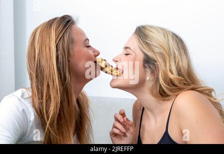 young girl couple sharing the same bun Stock Photo