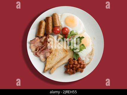 A plate with scrambled eggs, bacon, beans, sausages, tomatoes and croutons on a red background. Energy boost for the whole day Stock Photo