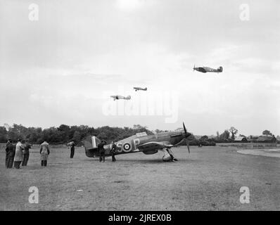 Royal Air Force Fighter Command, 1939-1945. Journalists from Dominions newspapers watch a flight of Hawker Hurricane Mark Is of No. 56 Squadron RAF taking off for a sortie over France from North Weald, Essex. In the foreground another Hurricane Mark I of the Squadron, P2764 'US-P', stands at its dispersal point near the perimeter track on the south-western edge of the airfield.