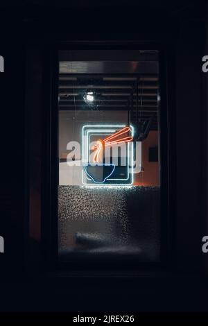 Neon sign on a dark background with bright bowl and noodles . Vertical shot Stock Photo