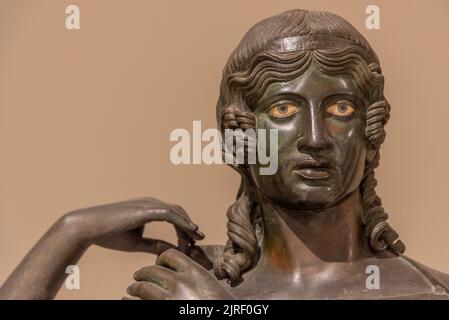 Close-up on face of ancient metal statue representing a girl with yellow eyes Stock Photo