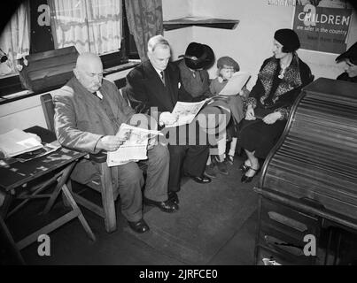 The work of the Citizens' Advice Bureau, Eldon House, Croydon, England, 1940 A group of civilians sit and wait their turn in the waiting room of the Citizens' Advice Bureau in Croydon. Men read newspapers to pass the time, whilst the women try to entertain the young girl accompanying her mother. Stock Photo
