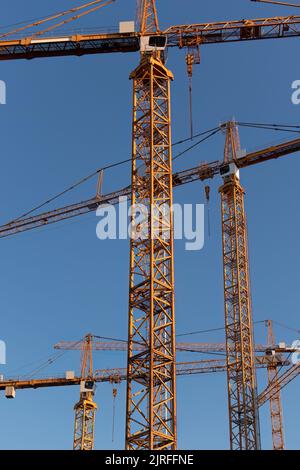 Close up of group of tower cranes against the blue sky in summer Stock Photo