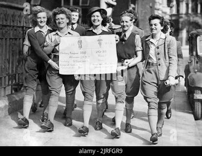 The Women's Land Army in Britain during the Second World War 700 Land Army girls from all parts of the country voicing their grievances at a meeting held in Caxton Hall, London demanding equal pay for equal work. Photo shows: Land Army girls arriving with a protest poster. Left to right, Miss Foster, London; Mrs Lloyd, Birmingham; Miss Brooks, Middlesex; Miss Hill, Yorkshire and Miss Millington, Secretary of the National Charter. The poster compares the allowances and conditions for the ATS with the Land Army. Stock Photo