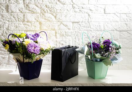 black empty paper bags and bouquets. Blank wall Stock Photo