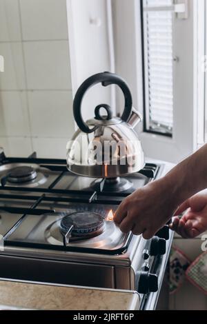 A man's hand with a match lights a gas burner or a gas stove in the kitchen. Stock Photo