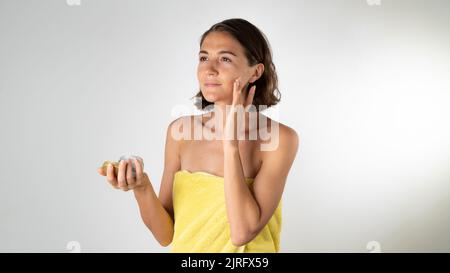A woman applies the cream on the face - spa at home Stock Photo