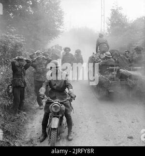 The British Army in the Normandy Campaign 1944 A mortar platoon carrier passes a group of German prisoners being escorted by a military policeman on a motorcycle, Caumont, 30 July 1944. Stock Photo