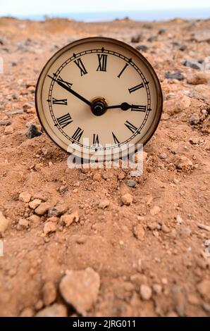 Classic Analog Clock In The Sand On The Rock Desert Stock Photo