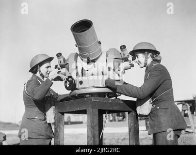 Two members of the Auxiliary Territorial Service (ATS) check the accuracy of anti-aircraft fire from a gun battery during the Second World War. The Auxiliary Territorial Service (ATS): Using a Kine-Theodolite - an instrument which records on film the bursts of anti-aircraft shells - two ATS women check the accuracy of the firing at an AA Battery at Manorbier. Stock Photo