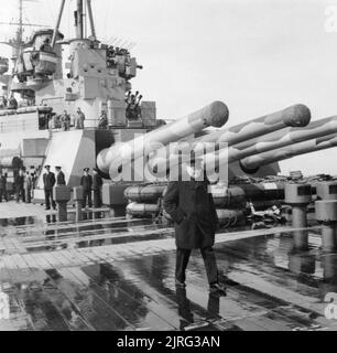 Winston Churchill on board the battleship HMS Prince of Wales during his journey to North America to meet President Roosevelt, August 1941. The Prime Minister Winston Churchill on board HMS Prince of Wales during his journey to North America to meet with President Roosevelt. The quadruple 14 inch guns of Y turret is visible in the background. Stock Photo