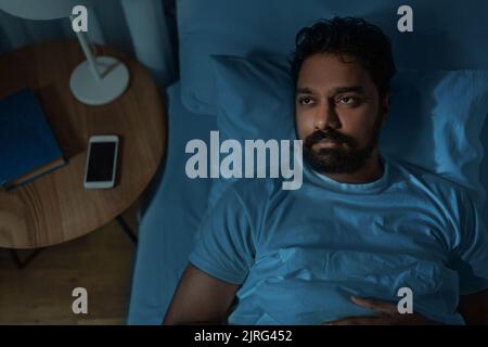 speelpess indian man lying in bed at night Stock Photo
