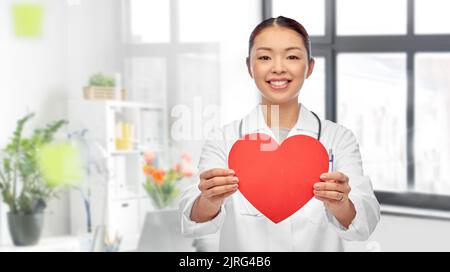 smiling asian female doctor holding red heart Stock Photo