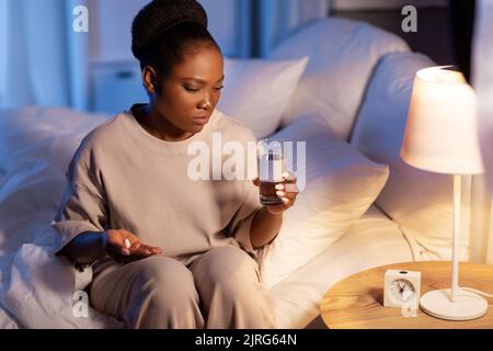 stressed african woman taking medicine at night Stock Photo