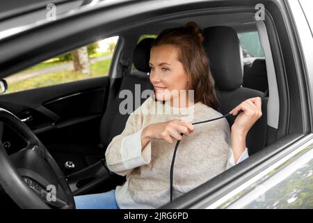 woman or female driver fastening seat belt in car Stock Photo