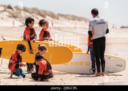 Aveiro, Portugal - August 19, 2022: A group of surfing students walk with their instructor to receive their lessons. Stock Photo