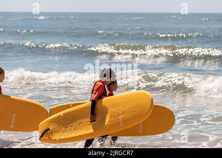 Aveiro, Portugal - August 19, 2022: A group of surfing students walk with their instructor to receive their lessons. Stock Photo