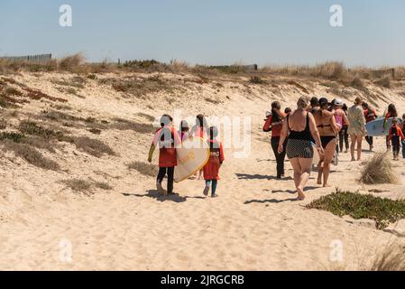 Aveiro, Portugal - August 19, 2022: A group of surfing students walk with their instructor to receive their lessons. Stock Photo