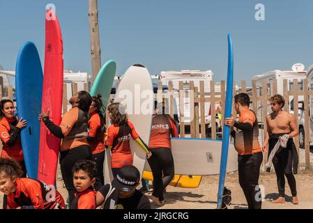 Aveiro, Portugal - August 19, 2022: people with wetsuits and pick up surfboards at the secreto surf school facilities. Stock Photo