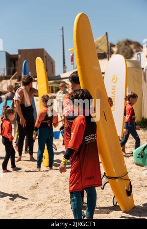 Aveiro, Portugal - August 19, 2022: people with wetsuits and pick up surfboards at the secreto surf school facilities. Stock Photo