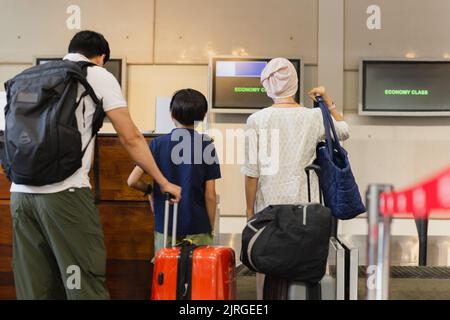 Family standing with luggage check in at airport. Stock Photo