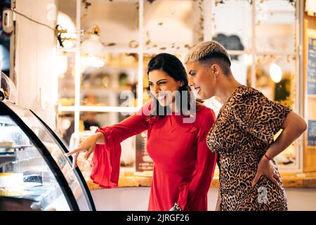A couple of women friends look at a showcase and choose which cakes to take in a cafe Stock Photo