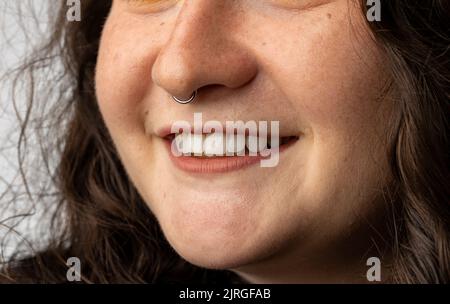 Close up of young woman with pierced nose smiling. Stock Photo