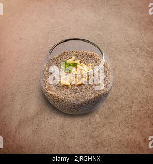 Salted caramel chia pudding decorated with almonds and mint in a glass jar Stock Photo