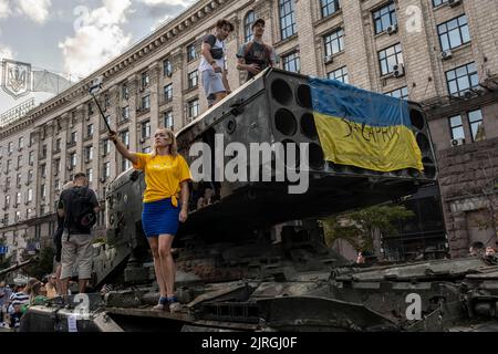 August 21, 2022, Kyiv, Kyiv Oblast, Ukraine: A woman takes a selfie as the people climb on the display of a destroyed Russian Multi Rocket Launch System Vehicle (MLRS) on the streets of Kyiv. As dedicated to the upcoming Independence Day of Ukraine, and nearly 6 months after the full-scale invasion of Ukraine on February 24, the country's capital Kyiv holds an exhibition on the main street of Khreschaytk Street showing multiple destroyed military equipment, tanks and weapons from The Armed Forces of The Russian Federation (AFRF)..As the Russian full invasion of Ukraine started on February 24, Stock Photo